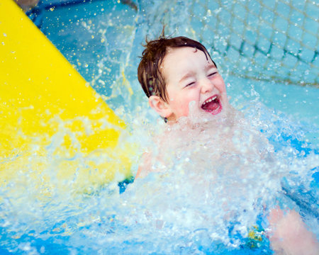 Boy splashes down after riding water slide