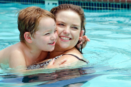 Mother and son cool off by playing in pool on hot summer day の写真素材