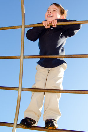 Young boy crawling over monkey bars on playground