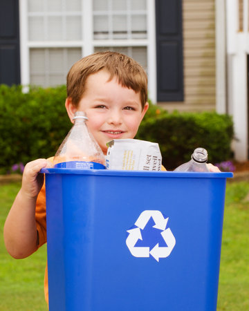 Recycling concept with young child carrying recycling bin to the curb at his houseの写真素材