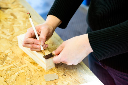 Parent draws stencil on wood block to be used as body for Pinewood Derby carの写真素材