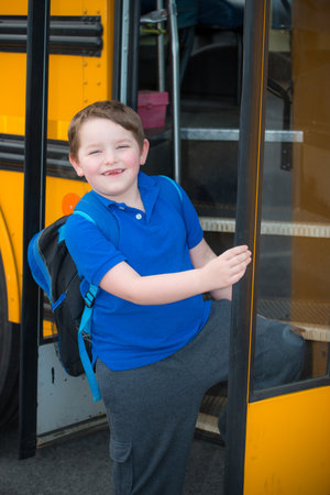 Happy child boarding school bus going back to school