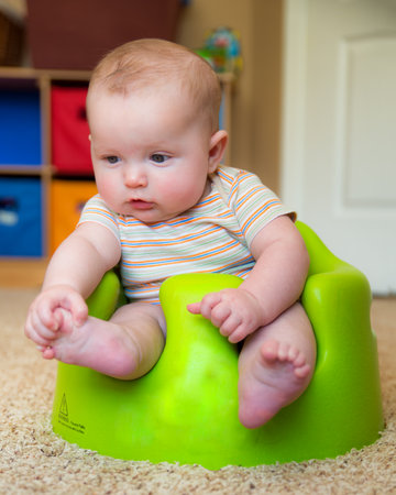 Baby boy using training Bumbo seat to sit up