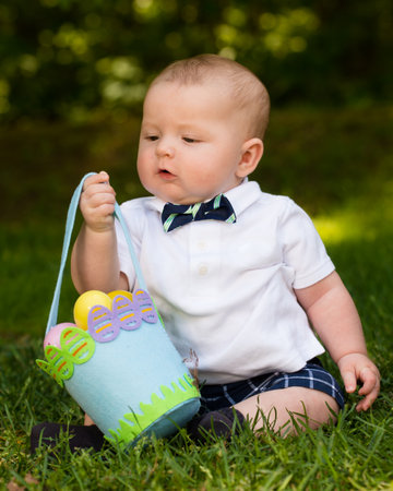 Cute infant baby boy playing with Easter eggs and basket