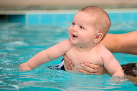 Happy infant baby boy enjoying his first swim in poolの写真素材