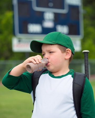Child baseball player drinking chocolate milk after gameの写真素材
