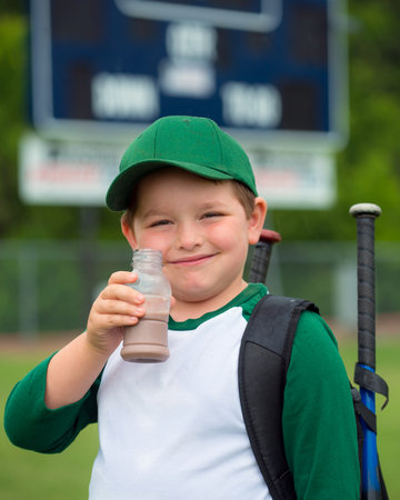 Child baseball player drinking chocolate milk after gameの写真素材