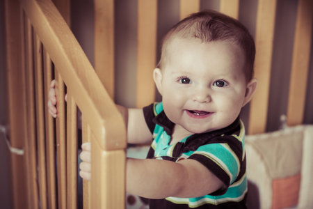 Happy baby standing up in his crib in image with vintage filterの写真素材