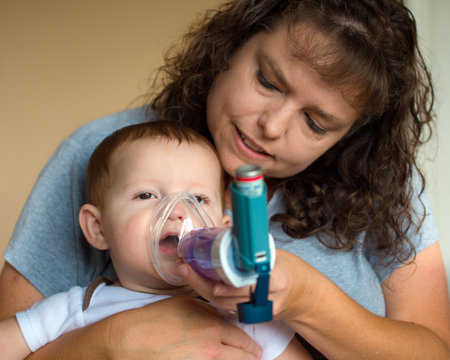 Infant getting breathing treatment from mother while suffering from illnessの写真素材