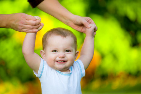 Smiling happy baby learning to walk outdoorsの写真素材