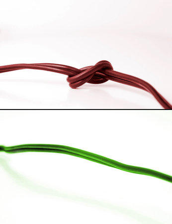 Conceptual photo showing two scenarios: problem and fixed problem. On top is red cable with knot - indicating problems. On bottom is green cable indicating problem free communication.の写真素材