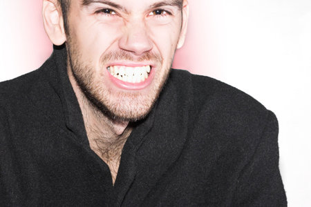 Young male with beard, looking angry at you and showing teeth. There is space for text.の写真素材