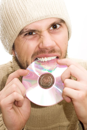 Man with hat holding CD in hands and trying to brake it with his teeth.の写真素材