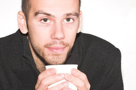 Young male with beard, blowing tea cup. Space for textの写真素材