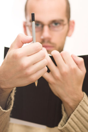 Man with beard and glasses, making eye-measure with pencil.の写真素材