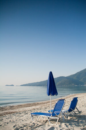 Clean summer photo. Blue summer umbrella with two chairs on blue skyの写真素材