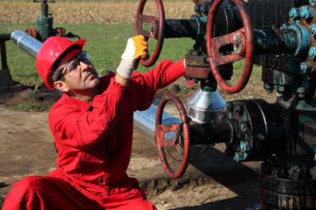 Oil worker turning valve on oil rig  の写真素材