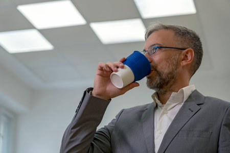 Elegant Businessman in Suit Drinking Coffee in Officeの写真素材