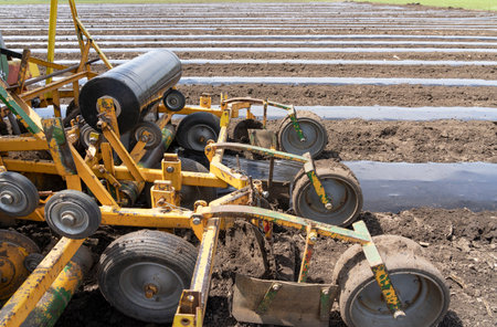 Tractor with agricultural equipment in the same pass dispenses fertilizer, lays down irrigation lines and rolls out a continuous of mulch plastic. Agricultural plastic mulch is used to prevent weeds growing and to reduce water loss from the soil. の写真素材