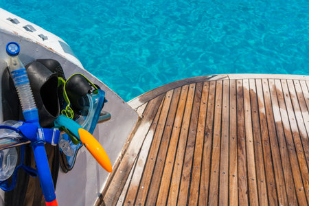 In the pictured boat with curved wooden deck wet,on the left  fins,mask,scuba rubber for snorkeling and in the background ocean blue  turquoise.の写真素材
