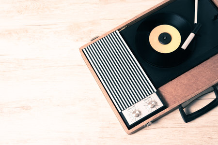 Gramophone with a vinyl record on wooden table, top view and copy space,photo desaturate and split...
