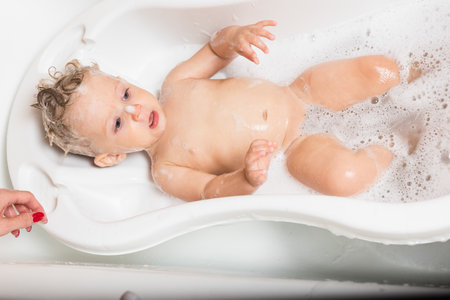 Little pretty wet baby boy in bath room lying on white background, horizontal picture.の写真素材