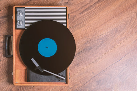 Vintage Gramophone with a vinyl record on wooden table, top view and copy space,photo.