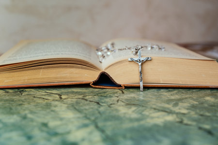Silver rosary and cross with jesus on the Bible on a green table. Religion at school,vintage style.の写真素材