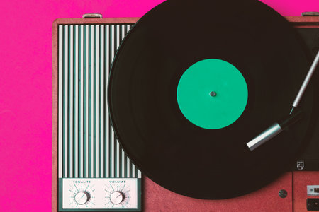 Old vinyl player and turnable on a fuchsia background. Entertainment 70s. Listen to music. Top view.