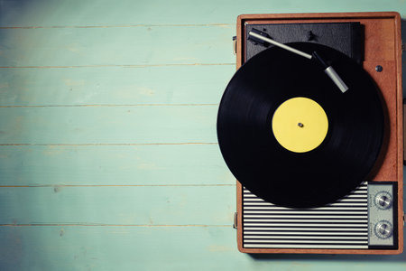 Vintage turntable with a vinyl record on green wooden table, top view and copy space.の写真素材