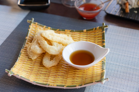 Ika Furai - Deep fried squid rings coated in panko breadcrumbs served with soy sauce and background chili sauceの写真素材