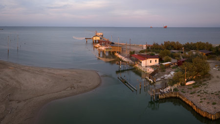View of fishing huts on shores of estuary at sunset, italian fishing machine, called "" trabucco "", Lido di Dante, Ravenna near Comacchio valley.の写真素材