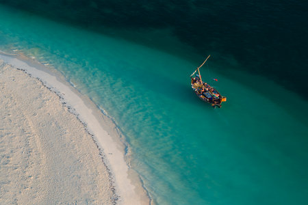High angle of view of dhow boat in the green ocean and wonderful white sandy beach, copy space, Zanzibar in Tanzania.の写真素材