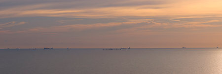 Panorama of dramatic sky at awesome sunset, flat sea at dawn, minimalist photo and mystery mood.
