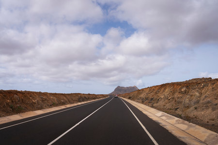A car driving on a road with mountains in the background.