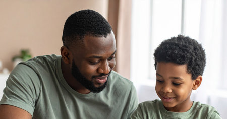 Father and son looking at each other in living room.の素材