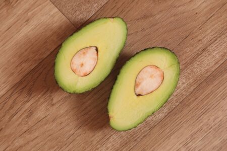 avocado cut in half on wood table