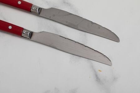 A sharp steak knife isolated on white marbler marbackground with red handle.