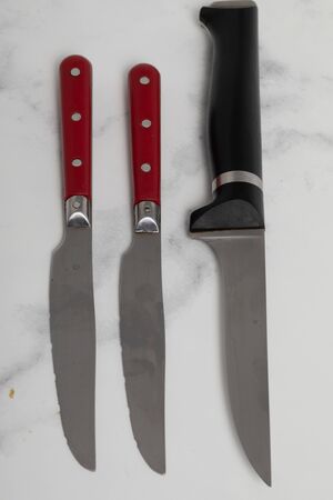 A sharp steak knife isolated on white marbler marbackground with red handle.の写真素材