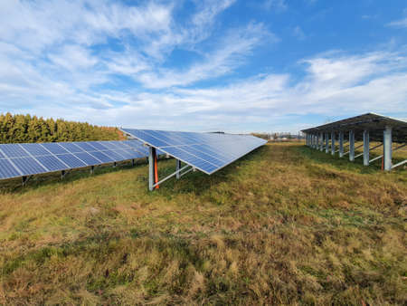 Solar cells on a meadow with blue sky with clouds. Solar panels, photovoltaic, alternative energy source. Sustainable resources concept.の写真素材
