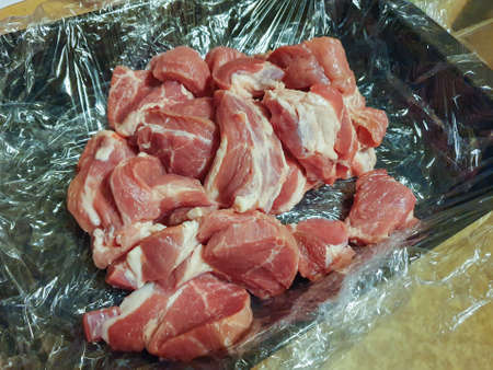 Pieces of pork infused with fat in a container. Preparation for cooking in the Dutch oven.の写真素材