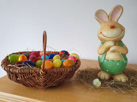 Figure of an Easter bunny with a basket of colorful eggs.の写真素材