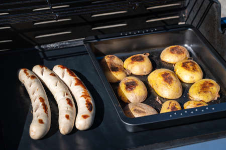 Fine sausage with potato halves on the grill. BBQ, grill photo, grilling.の写真素材