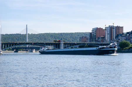 LiÃ¨ge, Belgium - August 22 2019: A boat on the Meuse river in front of the FragnÃ©e bridgeのeditorial素材
