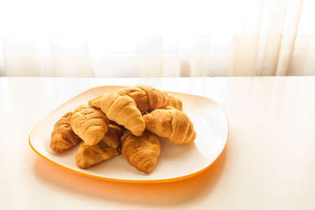 Mini croissants in a plate on a table with natural lightの写真素材