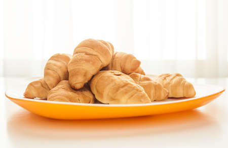 Mini croissants in a plate on a table with natural lightの写真素材
