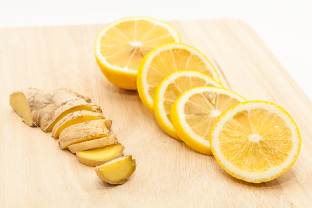 Sliced ginger and lemon slices on wooden cutting boardの写真素材