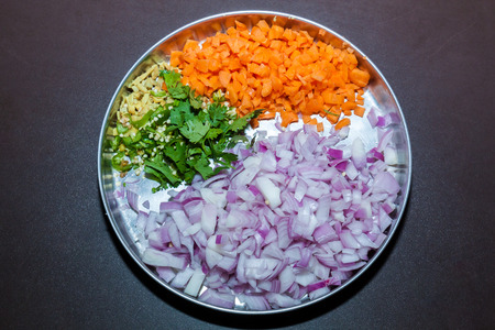 Top view of a plate of cut pieces of onion, carrot, coriander leaves, gingerの写真素材