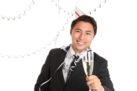Cheers! Young man wearing a suit, tie and party hat, holding a champagne glass. White background.の写真素材