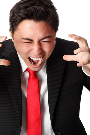 Frustrated businessman wearing a suit and red tie screaming. Whtie background.の写真素材